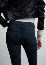 Jeans de corte skinny y tiro bajo, confeccionados en tejido denim elástico de algodón. Presentan diseño de cinco bolsillos, cierre frontal con cremallera y botón, y trabillas para cinturón.