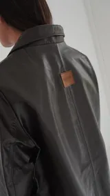 Blazer de cuero dorado metalizado, con bolsillos frontales aplicados, solapas clásicas y cierre con grandes botones de nácar.