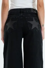 Jean de tiro medio-alto, color negro lavado, de corte recto y holgado. Presenta un gran estampado de estrella en color gris oscuro con brillo en los bolsillos traseros.