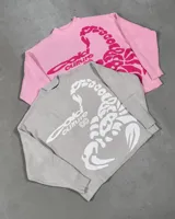 Suéter de punto color gris claro con diseño de escorpión en color blanco tejido en el frente. Presenta cuello redondo, puños y cintura con terminaciones acanaladas, y un corte holgado tipo boxy fit.