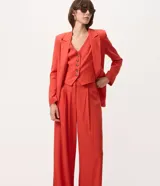 Chaleco de sastrería rojo con escote en V, sin mangas y cierre frontal con botones en contraste. Confeccionado en viscolino, de corte entallado y estilo elegante.