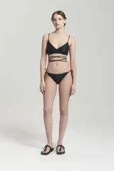 Conjunto de bikini negro con corpiño triangular de tiras finas y bombacha vedetina con tiras ajustables en los costados.