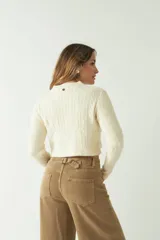 Sweater negro de punto con diseño trenzado, corte cropped, cuello redondo y mangas largas.