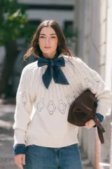 Sweater de lana tejido en color crudo, con cuello redondo y diseño calado en la zona del pecho y espalda. Presenta un corte holgado y puños acanalados.