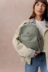 Mochila compacta de color beige, con compartimento principal con cierre, bolsillos laterales y bolsillo frontal con cierre oculto. Cuenta con correas regulables y acolchonadas y asa superior.