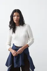 Polera de tejido de punto con textura calada y diseño de líneas verticales acanaladas. Presenta cuello alto y mangas largas con puños delicados, de silueta entallada.