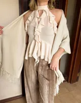 Blusa color marrón chocolate con escote halter, diseño sin mangas y múltiples volados verticales y horizontales que aportan volumen y movimiento.