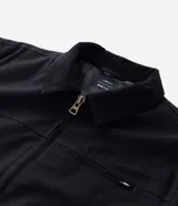 Campera tipo trucker de sarga color azul marino, con cuello de terciopelo al tono, cierre frontal de cremallera y bolsillo con cierre en el pecho.