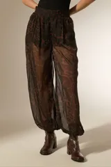 Pantalon de viscosa con diseño holgado, estampado animal print en tonos marrones y negros, cintura elástica y puños ajustados en los tobillos.