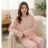 Conjunto de pijama de dos piezas confeccionado en tela de plush texturizada con diseño de rayas verticales en relieve. Incluye una remera de manga larga con cuello redondo y un pantalón de corte holgado. La remera presenta un pequeño bordado decorativo en el pecho.