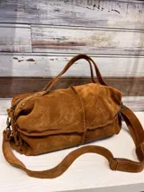 Bolso de mano tipo satchel color tostado, confeccionado en cuero con textura grabada tipo cocodrilo. Cuenta con doble asa superior, correa larga ajustable y extraíble para usar como bandolera, y cierre principal.
