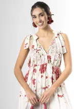 Vestido largo confeccionado en mezcla de tencel y lino, con fondo off white y estampado floral en tonos rosados, rojos y verdes. Cuenta con escote en V pronunciado, breteles anchos ajustables con lazos en los hombros, corte bajo el busto y falda amplia con volados escalonados.