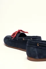 Mocasín tipo boat shoe color marrón, confeccionado en cuero, con cordones de cuero marrón y cordones decorativos azules.