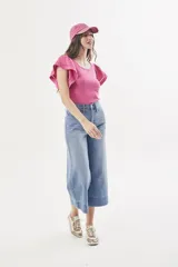 Remera fucsia de algodón peinado, con escote redondo, calce al cuerpo y mangas cortas amplias con detalles calados y vuelo.