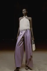 Pantalón de tiro alto con diseño cruzado tipo pareo, pernera ancha y detalle de lazada lateral. Presenta un acabado con efecto brillante.