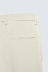 Pantalón de corte slim fit confeccionado en tejido elástico, con cintura elástica, cierre frontal con cremallera y botón, bolsillos laterales y bolsillos traseros de vivo.