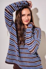 Sweater de punto con diseño de rayas horizontales en tonos ocre, marrón y crudo. Presenta cuello redondo, mangas largas y puños acanalados.