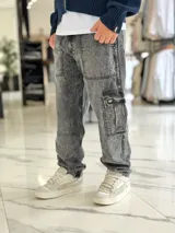 Pantalón cargo de jean azul claro, con bolsillos laterales tipo cargo en las piernas y bolsillos frontales aplicados, de corte ancho y holgado.