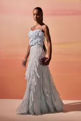 Falda larga de color celeste confeccionada en gasa y encaje. Presenta un diseño fluido con paneles asimétricos, capas con volados y detalles de encaje que aportan volumen y movimiento.