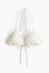 Top de bikini triangular color beige con textura de encaje, con copas con relleno extraíble y tiras para anudar al cuello y la espalda.