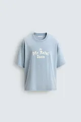 Camiseta de manga corta y cuello redondo, color celeste lavado, con estampado frontal en blanco que dice "The Mr. Rebel Dance".