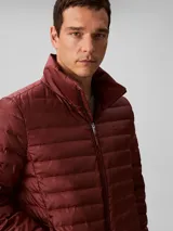 Campera puffer ligera de Calvin Klein, color bordó, con acolchado de canales horizontales, cuello alto y cierre frontal de cremallera. Presenta un diseño minimalista con logo de la marca en el pecho.