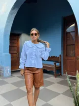 Bermuda de cuero sintético en color marrón, con diseño de corte recto, tiro medio y costuras verticales decorativas en el frente.