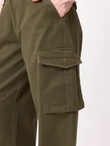 Pantalon cargo de corte recto y tiro medio, con estampado de camuflaje tipo bosque en tonos beige y marrones. Cuenta con bolsillos laterales tipo cargo con solapa y cierre de botón.