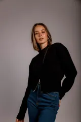 Suéter de punto color crema, con cuello redondo, manga larga y cierre frontal parcial que deja ver parte del abdomen.