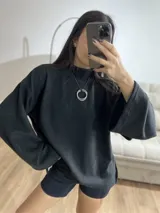 Poleron de cuello alto, color negro, con diseño holgado y mangas amplias.