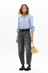 Camisa de algodón a rayas verticales celestes y blancas, con cuello mao, mangas largas abullonadas con puños elásticos y detalle de volado en la cartera de botones frontal.