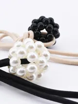 Set de dos coleros para el pelo, uno color beige y otro negro, ambos con adorno de cuentas.