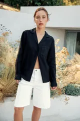 Bermuda de denim color marrón oscuro, de tiro medio y diseño relaxed fit, con cinco bolsillos, trabillas para cinto, bajo desflecado y cierre frontal con cremallera y botón.