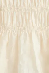 Blusa color beige, de mezcla de lyocell, con escote redondo, mangas cortas abullonadas y busto fruncido con tiras decorativas.