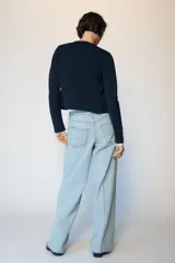 Jeans de tiro medio con diseño wide leg y pernera ancha. Presenta cinco bolsillos, cierre frontal con cremallera y botón, y detalle de raya planchada en el delantero y la espalda.