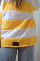 Sweater de punto a rayas horizontales amarillas y blancas, con cuello polo y mangas largas.