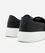 Championes tipo slip-on confeccionadas en cuero napa color negro, con elásticos laterales para un ajuste cómodo y suela robusta de goma en color blanco.