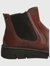Bota tipo Chelsea de cuero color marrón, con paneles elásticos laterales en color negro y suela de goma dentada.