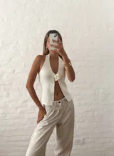 Top blanco con escote halter y detalle de flor en el centro.