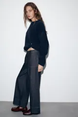 Pantalón de jean tiro medio con corte culotte, pernera ancha y corta. Presenta bolsillos delanteros de plastrón, costuras decorativas verticales y cierre frontal con cremallera y botón.