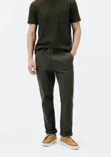 Pantalón de vestir color verde oscuro, de corte slim, con bolsillos laterales y traseros. Se ajusta a la cintura con botón y cierre.