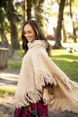 Poncho de lana merino color negro, con cuello alto, diseño amplio y terminaciones con flecos en todo el borde.