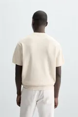 Camiseta negra de punto perlado, corte regular fit, cuello redondo, manga corta y rib en los acabados.