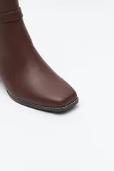 Bota corta de caña baja color negro, con puntera cuadrada, taco medio y tira decorativa con hebilla metálica en el lateral.