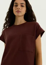 Vestido corto marrón de corte recto y holgado, con mangas cortas con vuelta, cuello redondo y un bolsillo aplicado en el pecho.