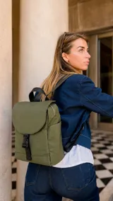 Mochila de nylon color azul, con tapa frontal y cierre de broche tipo hebilla. Cuenta con correas regulables negras, asa superior, bolsillos laterales y bolsillo trasero con cierre.