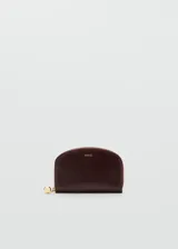 Billetera de mano color bordó con diseño semicircular, cierre perimetral con tirador metálico dorado y logo de la marca grabado en el frente.