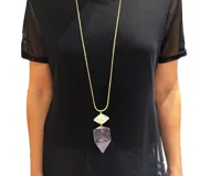 Collar largo con cadena dorada y dije geométrico de resina en tonos rosa y blanco.