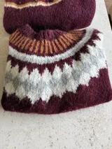 Sweater de punto tejido a mano en mohair, con diseño de canesú estampado en tonos azul, rojo, blanco y turquesa. Presenta cuello redondo y mangas largas.