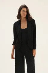 Blazer negro con estampado de lunares blancos, de corte recto y solapas clásicas.